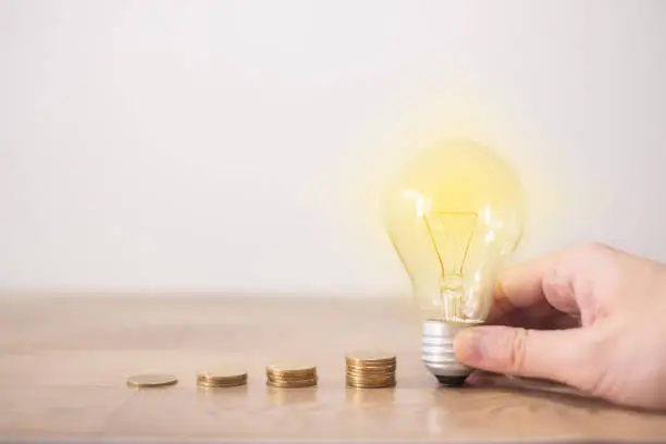 new idea concept with coins stack, young women hand holding light bulb with new knowledge on wooden backgrounds and new idea concept save power to save the earth