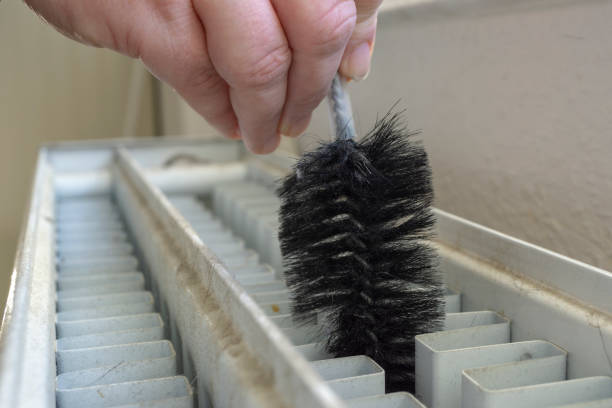 Close up of woman's arms cleaning and polishing kitchen cabinets.