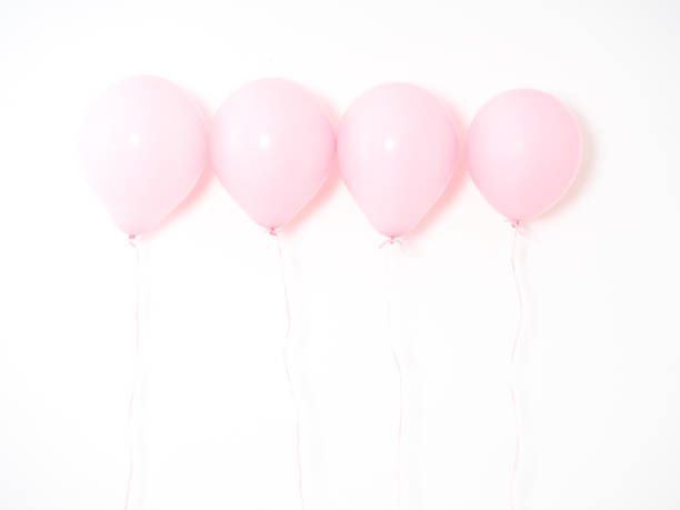 istock Female hand holding pink balloons on gray wall 1136107763