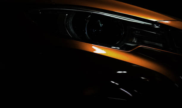 istock Closeup headlight of shiny orange luxury SUV compact car. Elegant electric car technology and business concept. Hybrid auto and automotive. Car parked in showroom or motor show. Car dealership. 1136108564