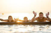 happy family with one child in lake at sunset