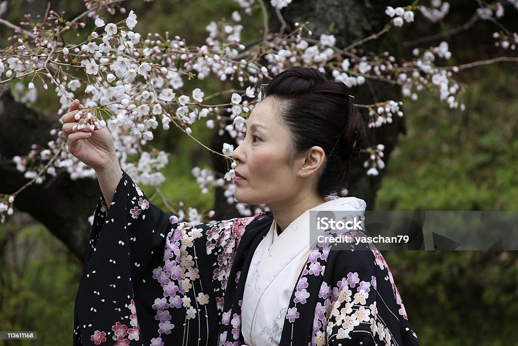 Mujer con flores de cerezo japonés - Foto de stock de Mujeres maduras libre de derechos