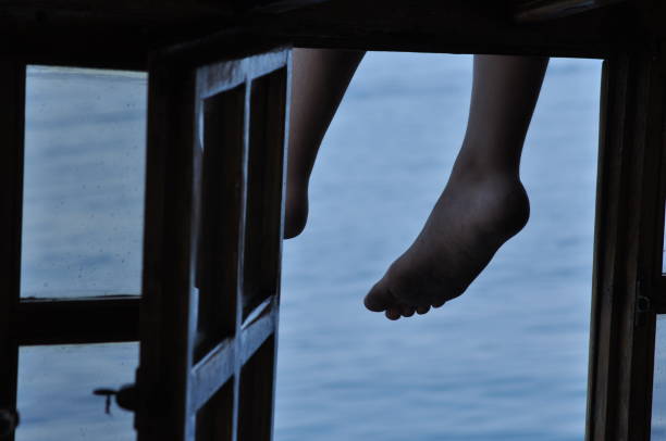 istock Legs dangling from the deck. Sea view through the open window. 1136113896