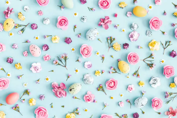 Photo of Easter eggs, colorful flowers on pastel blue background. Easter, spring concept. Flat lay, top view