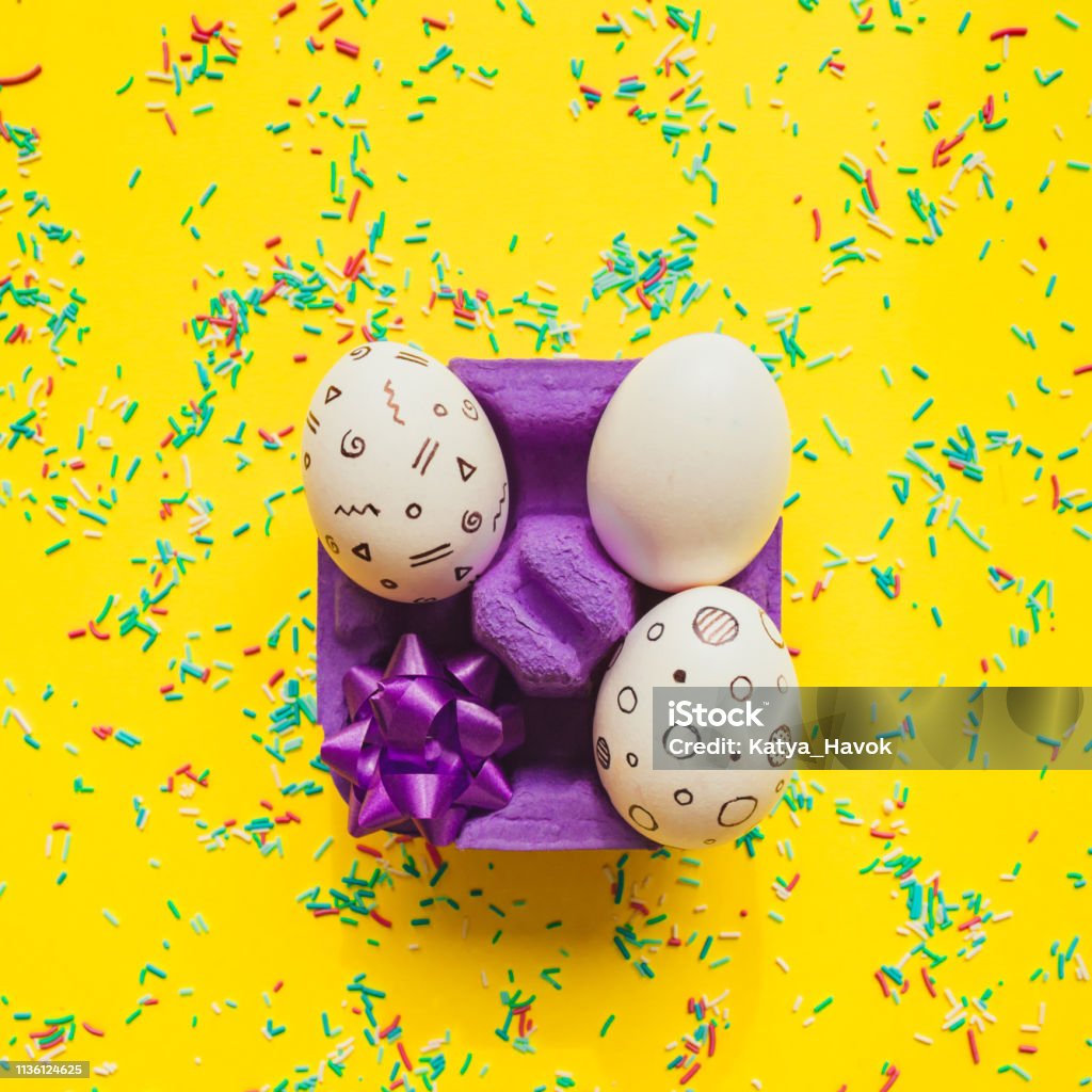 Easter eggs with memphis style print  with bow in box on yellow bright background with confetti.  Happy spring holidays concept. Abstract Stock Photo