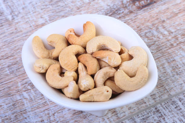 istock nuts cashews in white bowl on wooden background. Selective focus. 1136127988