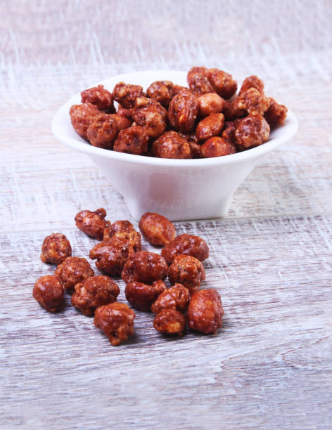 istock Sugared Hazelnuts in a white bowl on a wooden background. Hazelnuts in sugar glaze. Selective focus. 1136129717