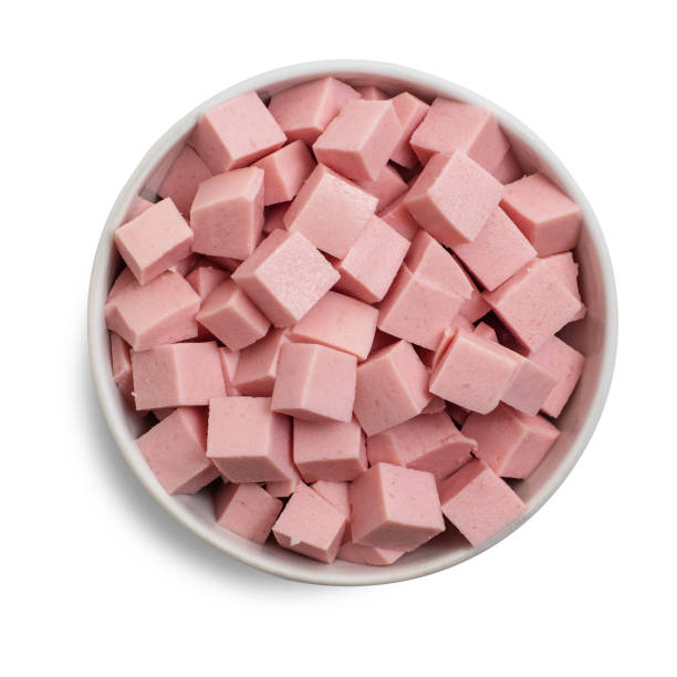 istock Boiled sausage cut into cubes in bowl isolated on white background. Top view 1136133080