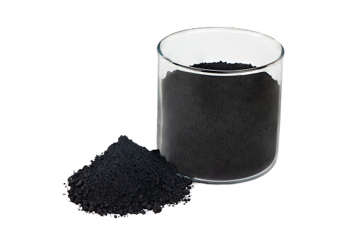 Black powder activated charcoal in glass on white background