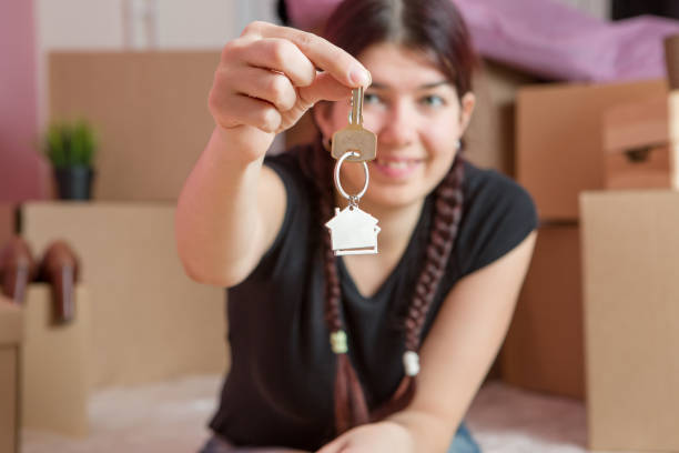 istock Image of young brunette with keys from apartment against blank wall 1136136132