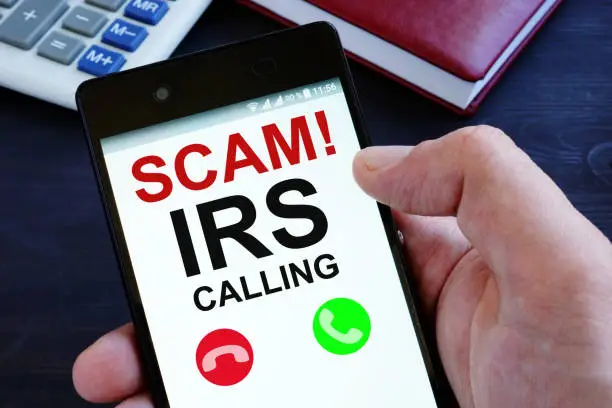 Photo of Hand is holding phone with irs scam calls.