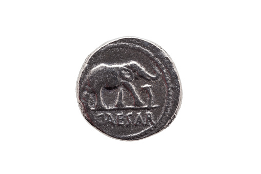 Silver Roman denarius coin replica of Roman emperor Julius Caesar celebrating his conquest of Gaul obverse showing an elephant and serpent isolated on a white background
