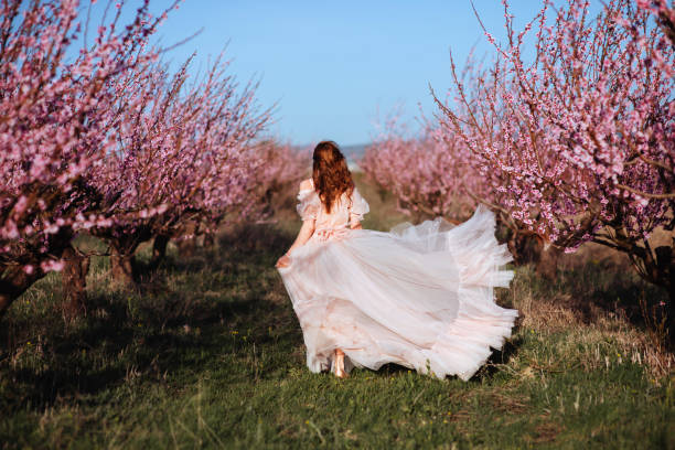 istock Beautiful young girl under the flowering pink tree 1136143640
