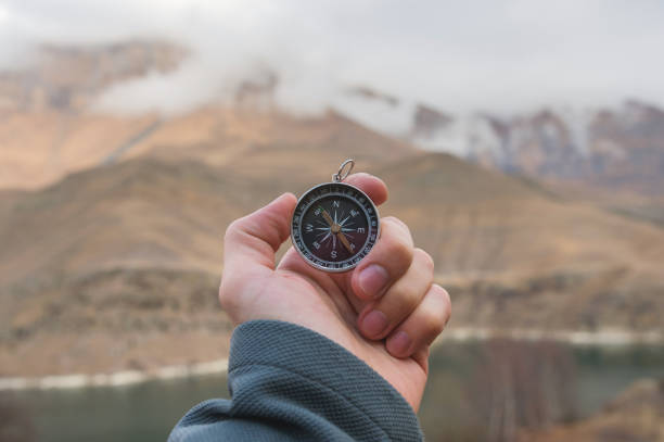 istock A male Hiker is looking for a direction with a magnetic compass in the mountains in the fall. Point of view shot. Man's hand with a watch bracelet holds a compass 1136149184