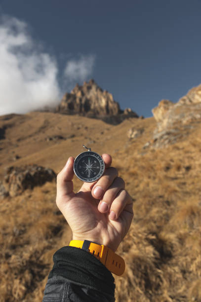 istock A male Hiker is looking for a direction with a magnetic compass in the mountains in the fall. Point of view shot. Man's hand with a watch bracelet holds a compass 1136149248