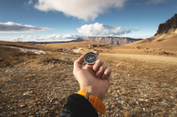 istock A male Hiker is looking for a direction with a magnetic compass in the mountains in the fall. Point of view shot. Man's hand with a watch bracelet holds a compass 1136149672