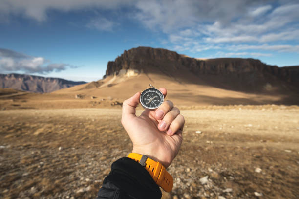 istock A male Hiker is looking for a direction with a magnetic compass in the mountains in the fall. Point of view shot. Man's hand with a watch bracelet holds a compass 1136149680