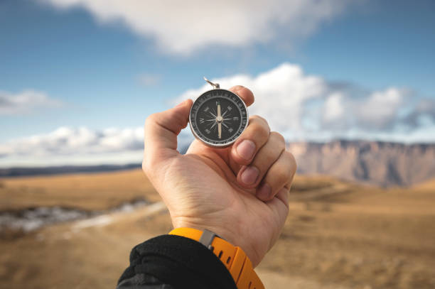 istock A male Hiker is looking for a direction with a magnetic compass in the mountains in the fall. Point of view shot. Man's hand with a watch bracelet holds a compass 1136149714