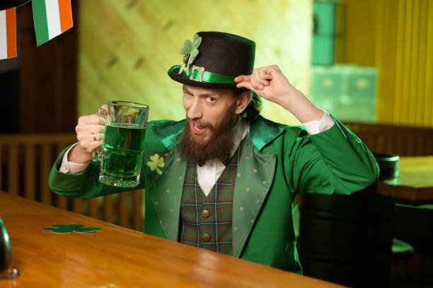 istock Dark-haired bearded young man in a leprechaun hat looking amused 1136151753