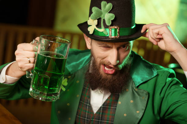 istock Dark-haired bearded young man in a leprechaun hat with shamrock having fun 1136151771