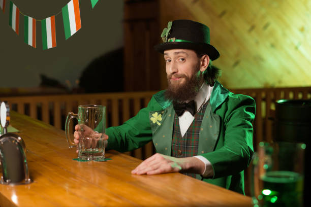 istock Dark-haired bearded young man in a leprechaun costume looking merry 1136151777