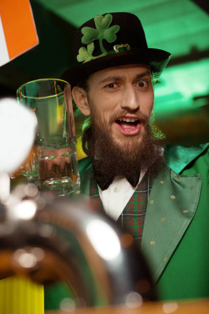 istock Dark-haired bearded young man in a leprechaun costume feeling wonderful 1136151784