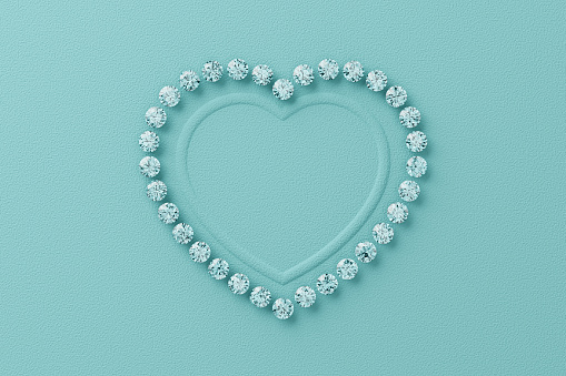 Heart-shaped frame made from small diamonds on turquoise textured paper background