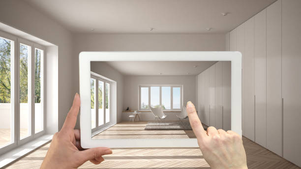 istock Augmented reality concept. Hand holding tablet with AR application used to simulate furniture and design products in empty interior with parquet floor, modern white living room 1136156666