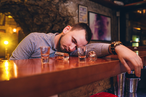 Young caucasian drunk man sleeping in bar.