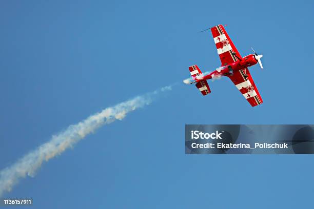 Red And White Airplane With The Trace Of White Smoke Behind It In The Sky In The Airshow Stock Photo - Download Image Now