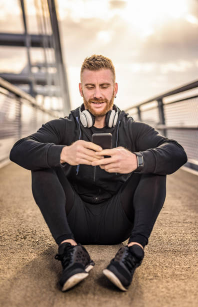 istock Sporty young man using phone on a bridge. 1136158039