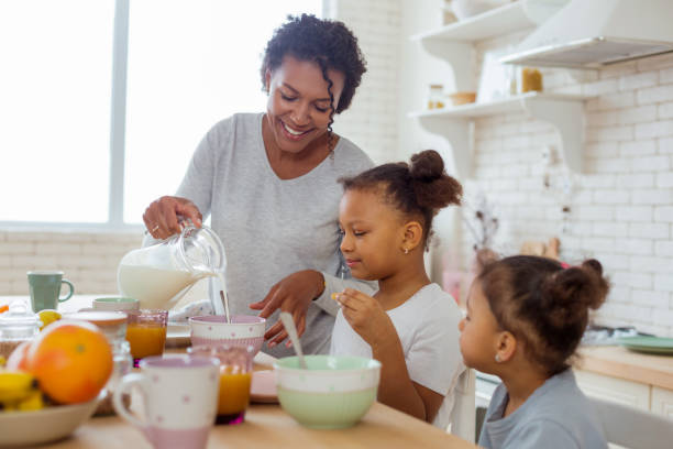 istock Cheerful young woman pouring down milk into bowl 1136159613