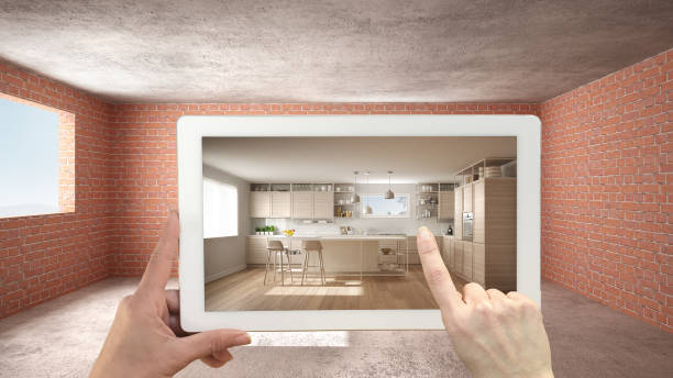 istock Augmented reality concept. Hand holding tablet with AR application used to simulate furniture and design products in interior construction site, classic kitchen with island and stools 1136160733