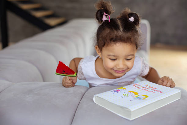 istock Cheerful dark-skinned girl looking at new book 1136161635