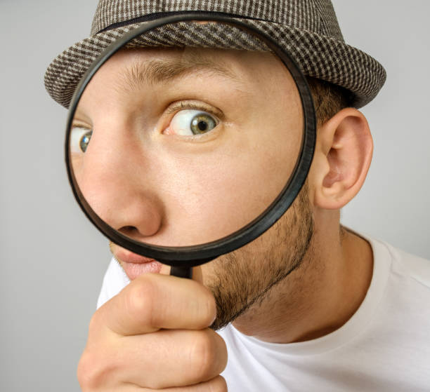 istock Astonished man looking through a magnifying glass on gray background 1136169718