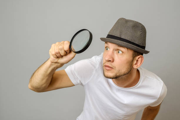 istock Astonished man looking through a magnifying glass on gray background 1136169719