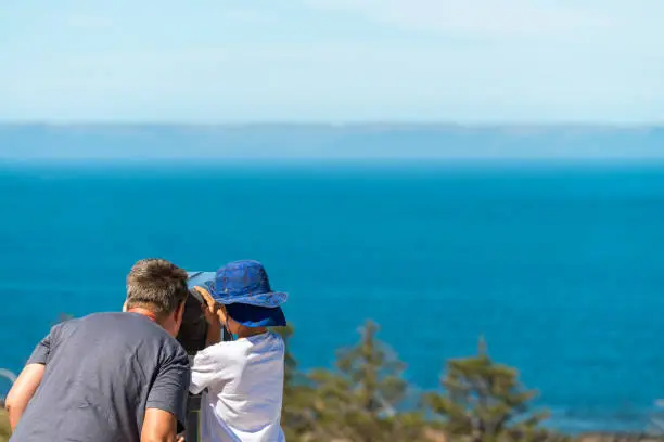 Photo of Grandfather and grandson observing Kangaroo Island coast through outdoor binocular