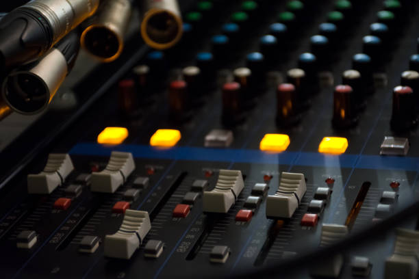 Sound mixer control panel on dark light background in audio control room.