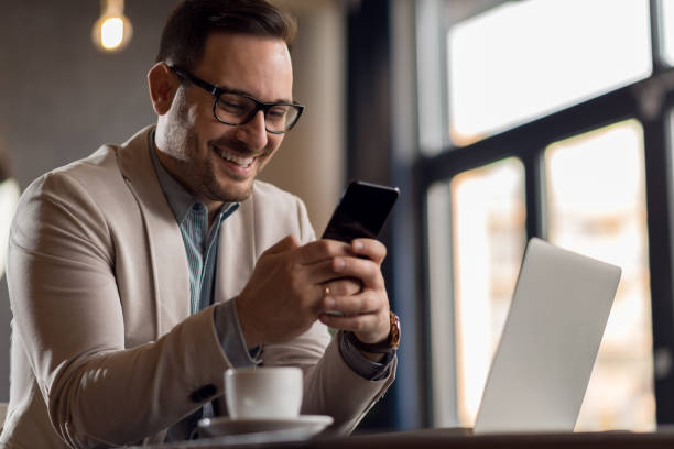 istock Young businessman in a cafe using cell phone and laptop 1136176391