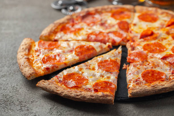istock Sliced hot pepperoni pizza on a brown background. 1136176433