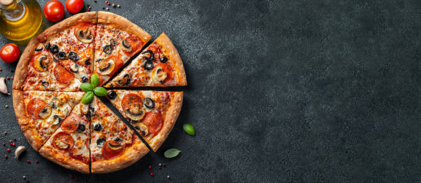 Tasty pepperoni pizza with mushrooms and olives. Tasty pepperoni pizza with mushrooms and olives on black concrete background. Top view of hot pepperoni pizza. With copy space for text. Flat lay. Banner. pizza stock pictures, royalty-free photos & images
