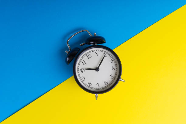 Black vintage alarm clock on a blue and yellow background
