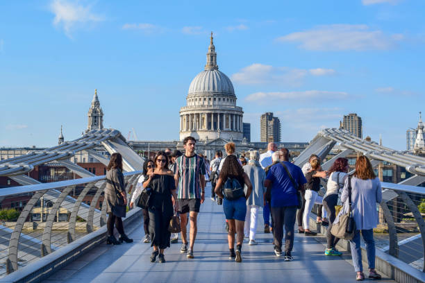 menschen, die die millenium bridge über die themse in london überqueren - millennium footbridge stock-fotos und bilder