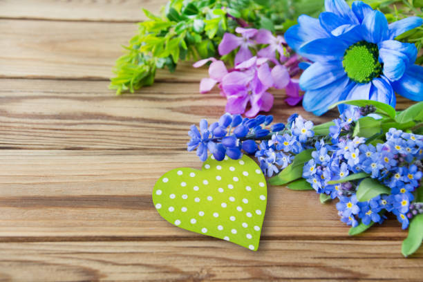 Flowers and heart against wooden background