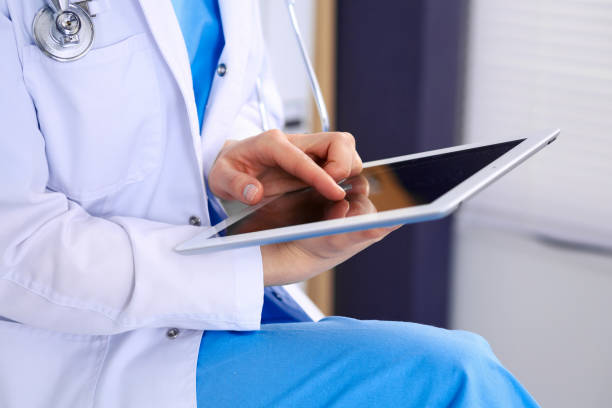 istock Woman doctor using white tablet computer while sitting at chair in hospital, close-up. 1136181225