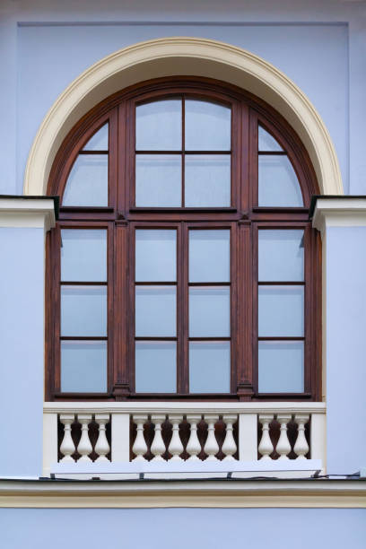 istock Close up view on a arched window with wooden frame and decorative white fence on bottom on a  facade of blue ancient building 1136182591