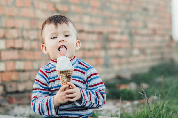 istock little cute boy boy boy three years eating ice cream very appetizing on brick wall background 1136185645