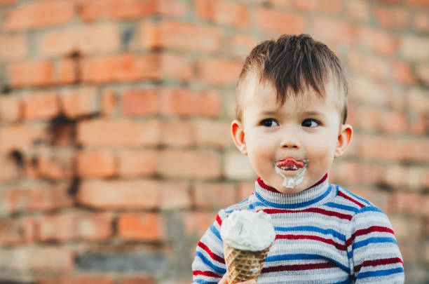 istock little cute boy boy boy three years eating ice cream very appetizing on brick wall background 1136186896