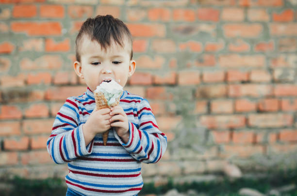 istock little cute boy boy boy three years eating ice cream very appetizing on brick wall background 1136187034