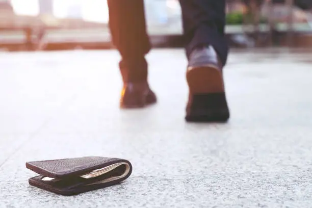 Photo of businessman had lost leather wallet with money on the street. Close-up of wallet lying on the sidewalk in during the trip to work.